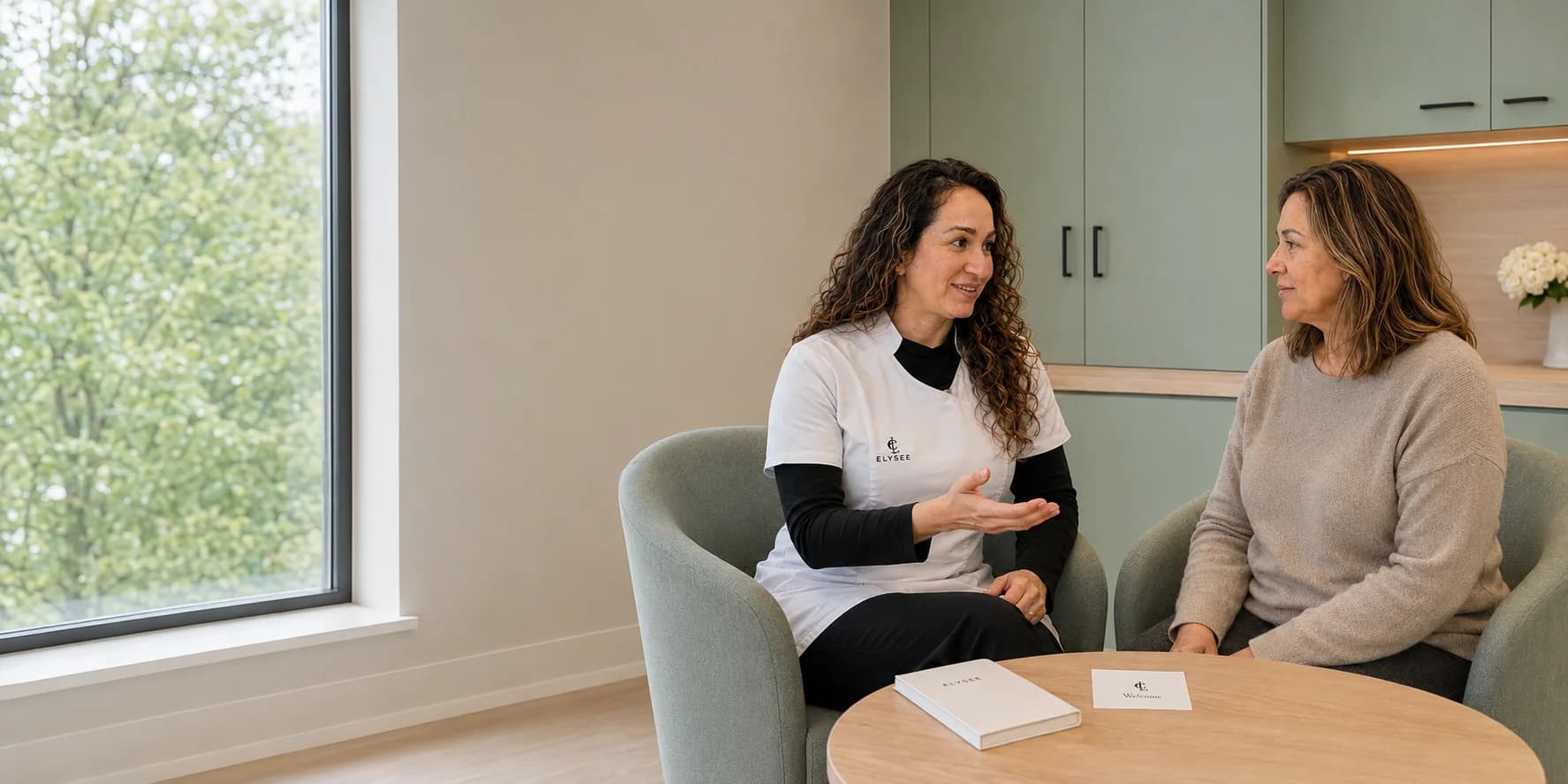 Drs. Donija Azim bespreekt de behandeling met een cliënte aan tafel in de Elysee-kliniek